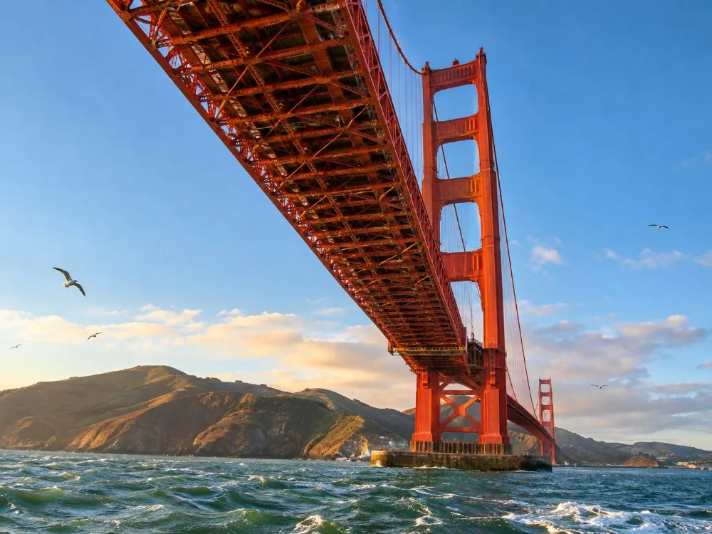 The underside of the Golden Gate Bridge deck and the south tower, seen from a boat on the bay